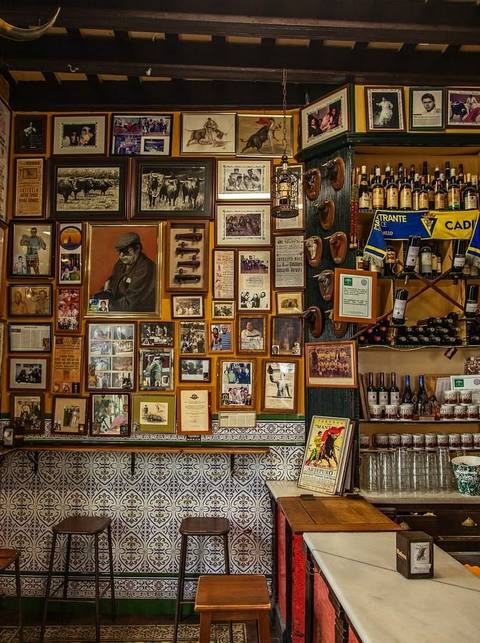 Barra de un bar de toda la vida, con fotos antiguas y botellas en las paredes